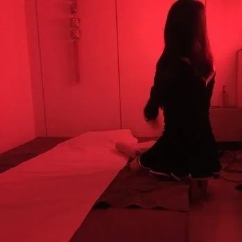 La masseuse du salon agenouillée sur le tatami, sous une lumière rouge tamisée