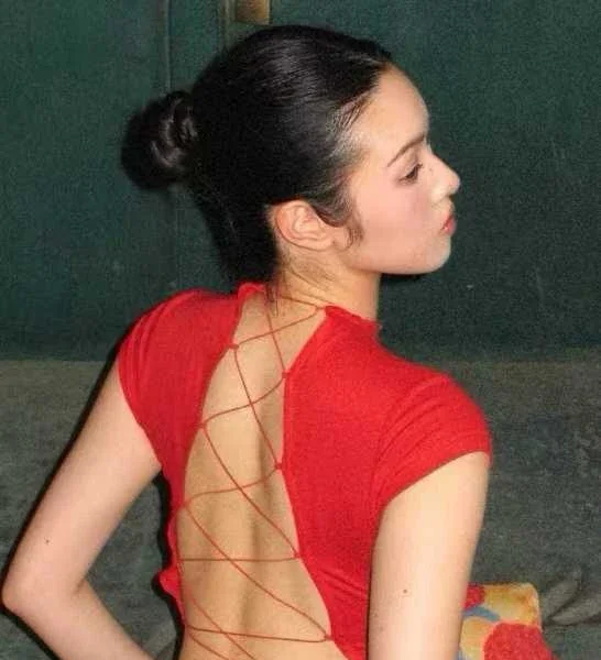 Une masseuse de dos, en haut rouge lacé, le visage tourné de profil