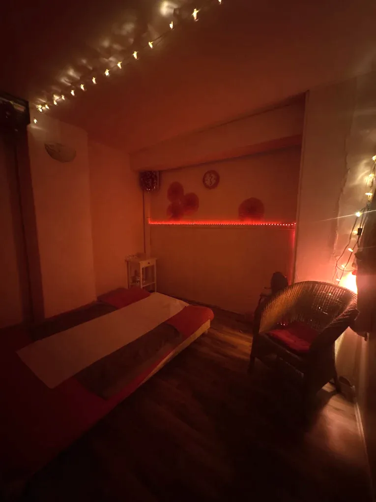 Salle de massage éclairée de guirlandes lumineuses, avec un tatami et un fauteuil en rotin